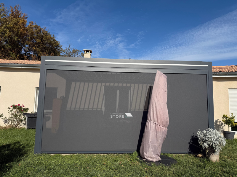 Pergola bioclimatique adossée structure aluminium extrudé avec stores ZIP motorisés et évacuation intégrée